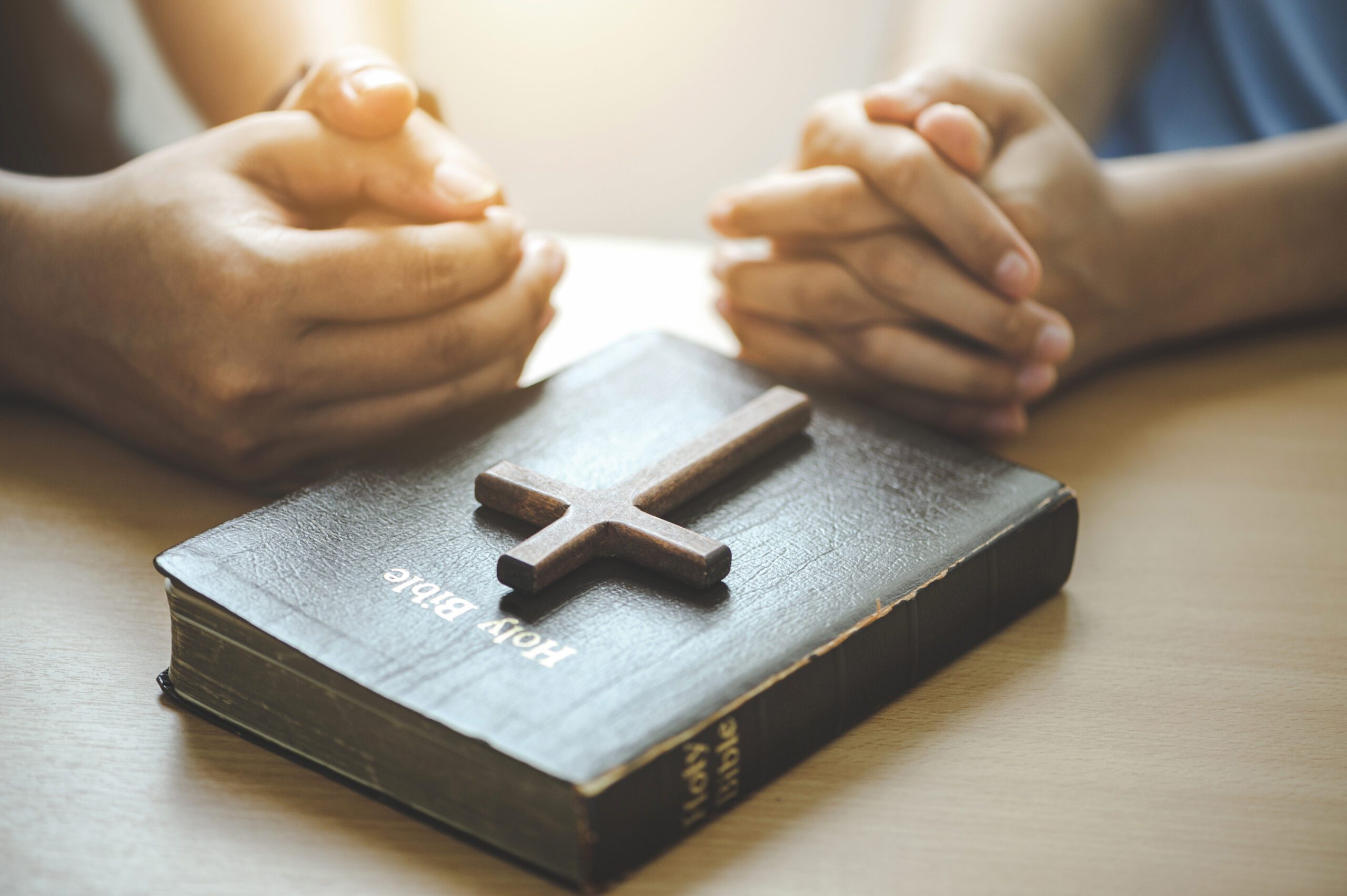 Hands of Christian group Pray for god blessing with the bible on a wooden table. begging for forgiveness and believe in goodness. Christian life crisis prayer and worship to god.